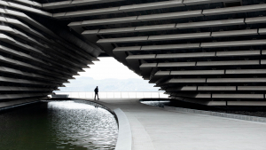 silhouette person walking through tunnel under V and A building Dundee