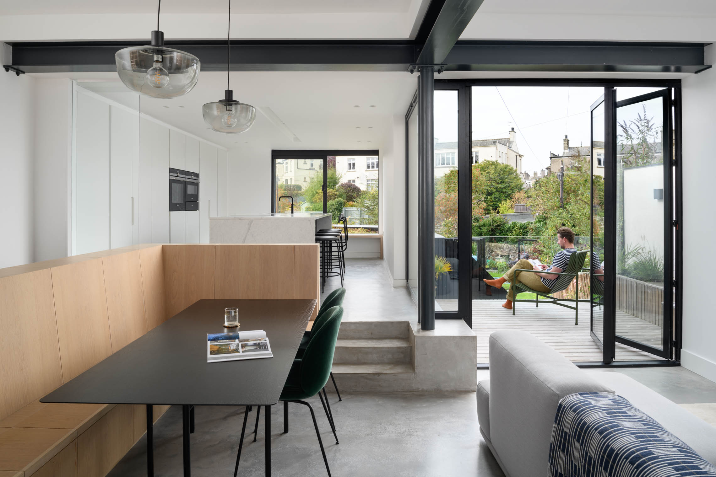 Minimal architectural interior living space with person reading outside on the balcony